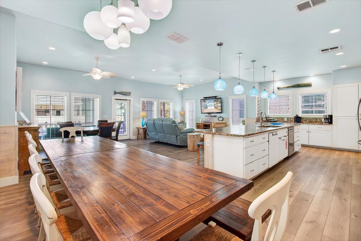 Gather around the stunning reclaimed wood dining table in this open-concept haven, where coastal charm meets modern comfort for your perfect getaway.