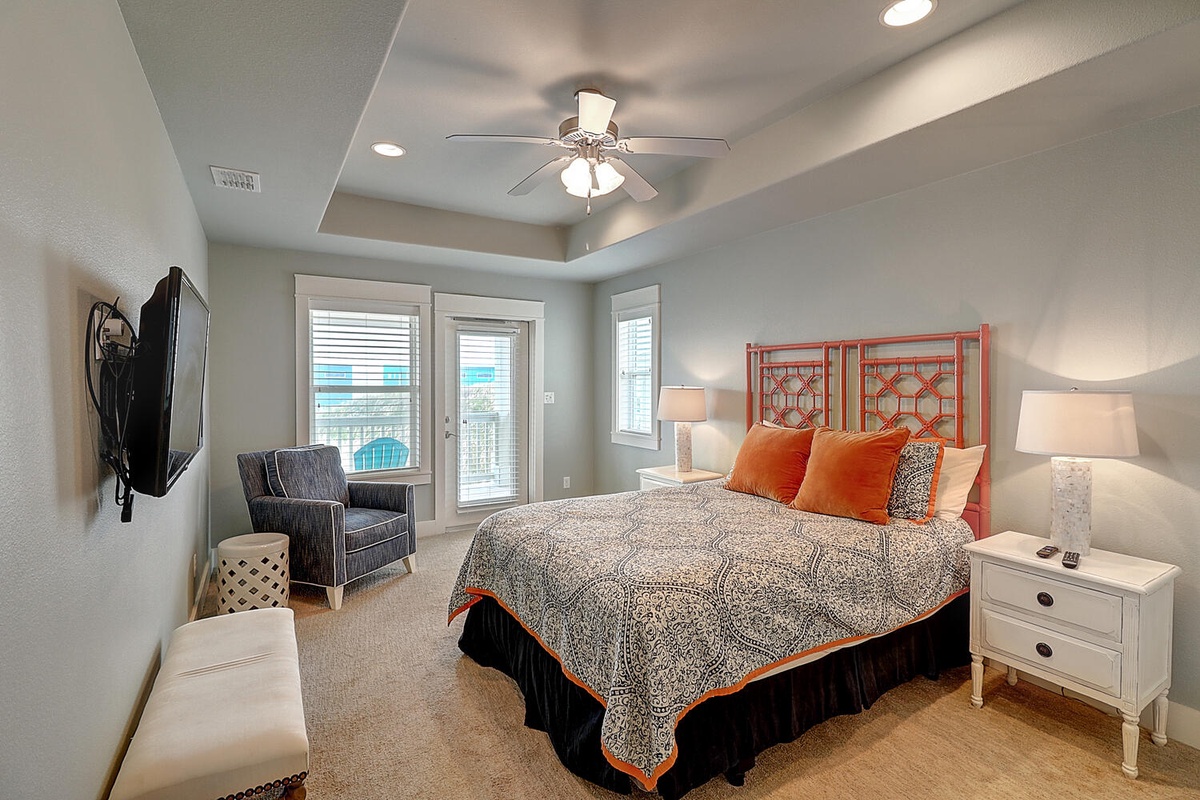Sink into comfort in your stylish bedroom featuring a plush king bed, ceiling fan, and relaxing seating area with natural light.