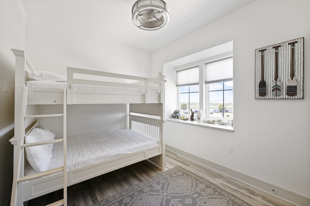 Cozy white bunk beds with soft linens create the perfect retreat for kids or extra guests in this bright, cheerful room.