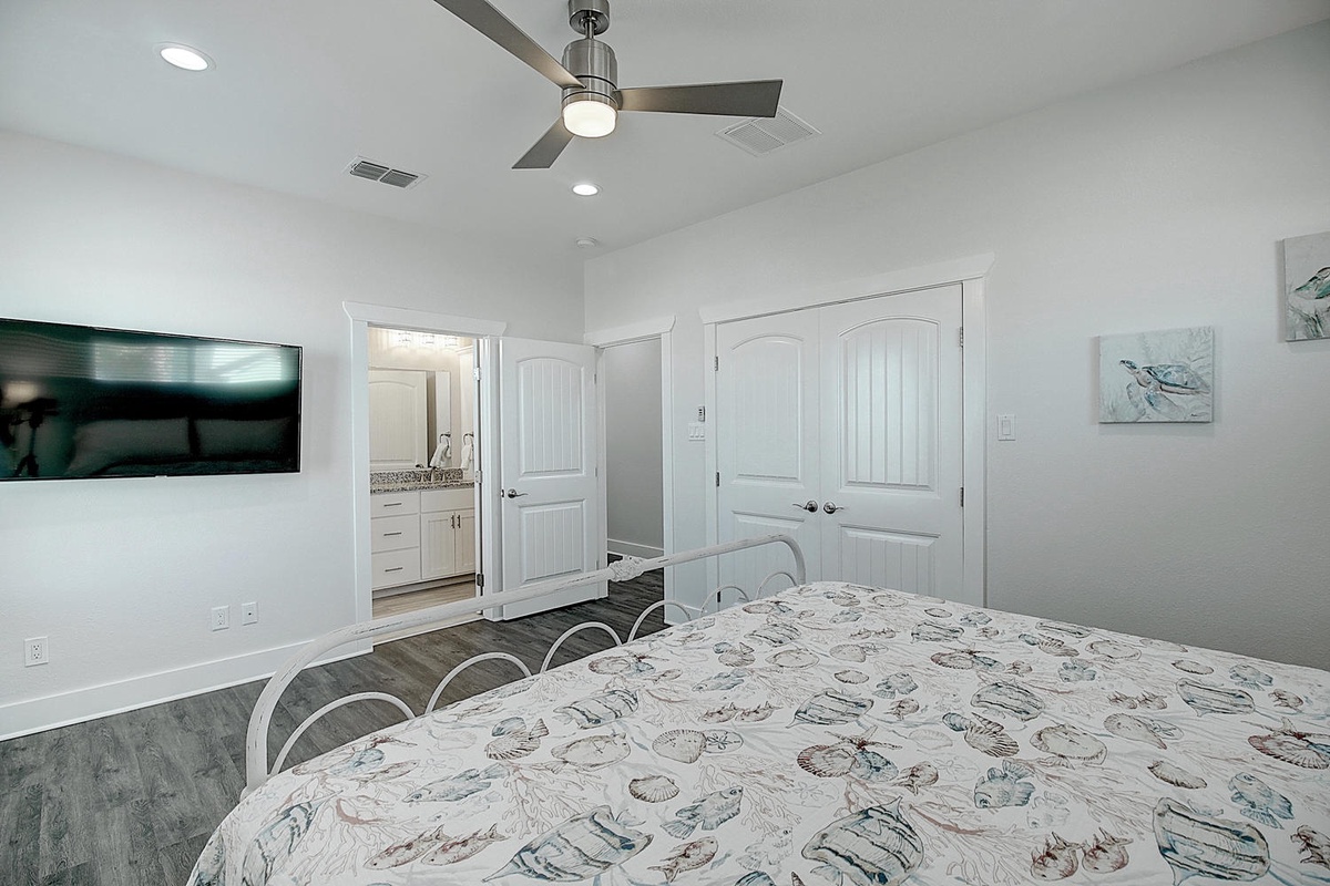 Your serene bedroom features a comfy bed, modern ceiling fan, and flat-screen TV for perfect relaxation after beach days.