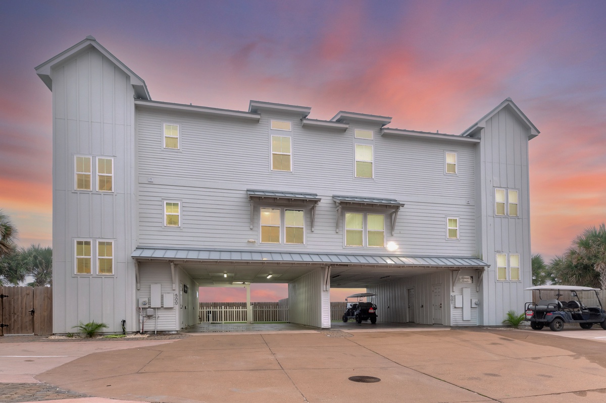 Modern beachside duplex with covered parking and stunning sunset backdrop creates the perfect coastal retreat setting.