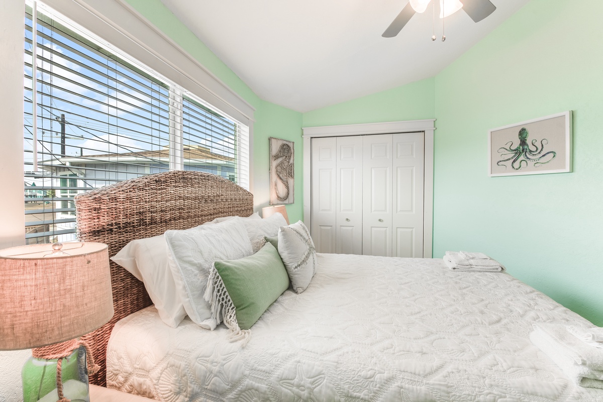 Your peaceful bedroom retreat features soft mint walls, woven headboard, and coastal artwork that creates the perfect sanctuary for restful nights.