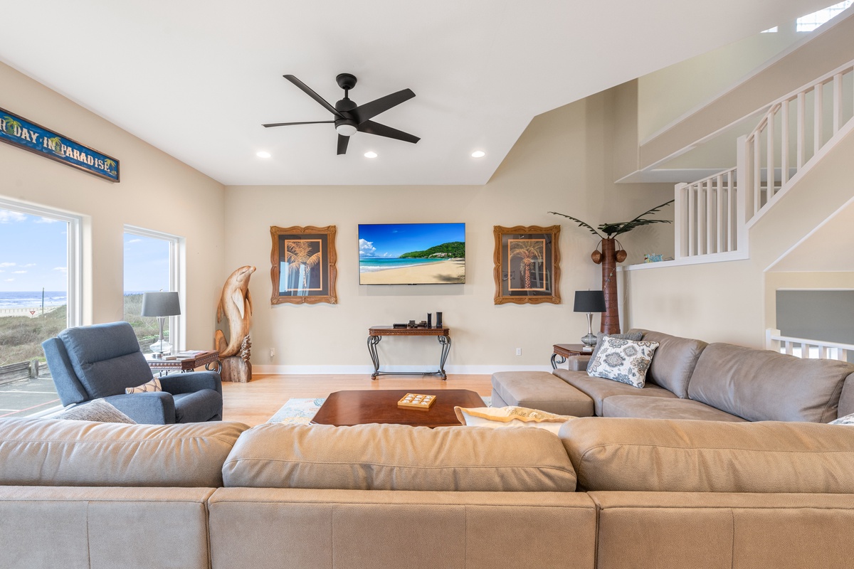 Relax in your spacious living room with comfortable seating, tropical decor, and natural light streaming through large windows.