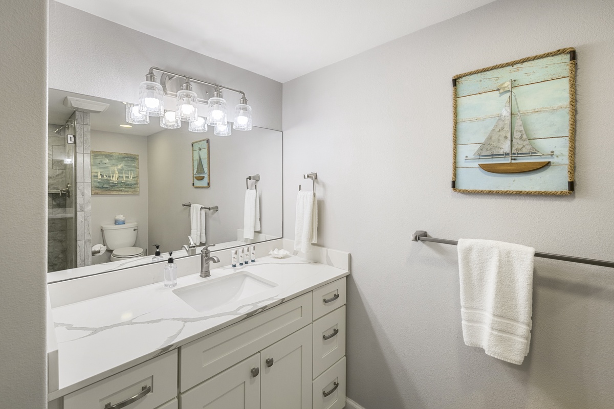 Step into your coastal-themed bathroom where fresh white linens await and nautical artwork creates a serene seaside escape.
