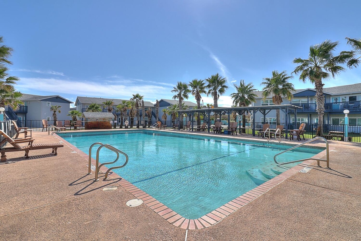 Dive into crystal-clear waters surrounded by swaying palms and comfortable loungers, where your perfect poolside retreat awaits under sunny skies.