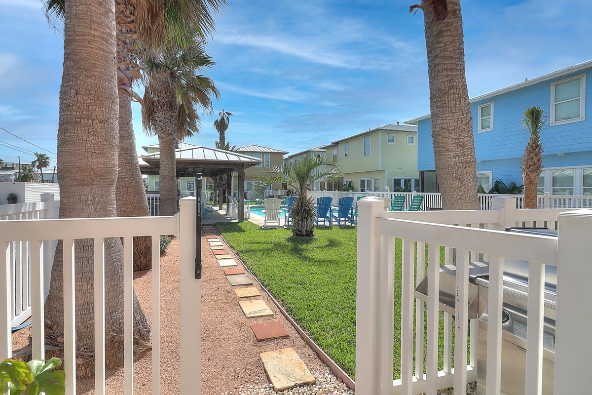 Tropical beachside property featuring colorful cottages, lush palm trees, and resort-style pool area in a coastal setting.
