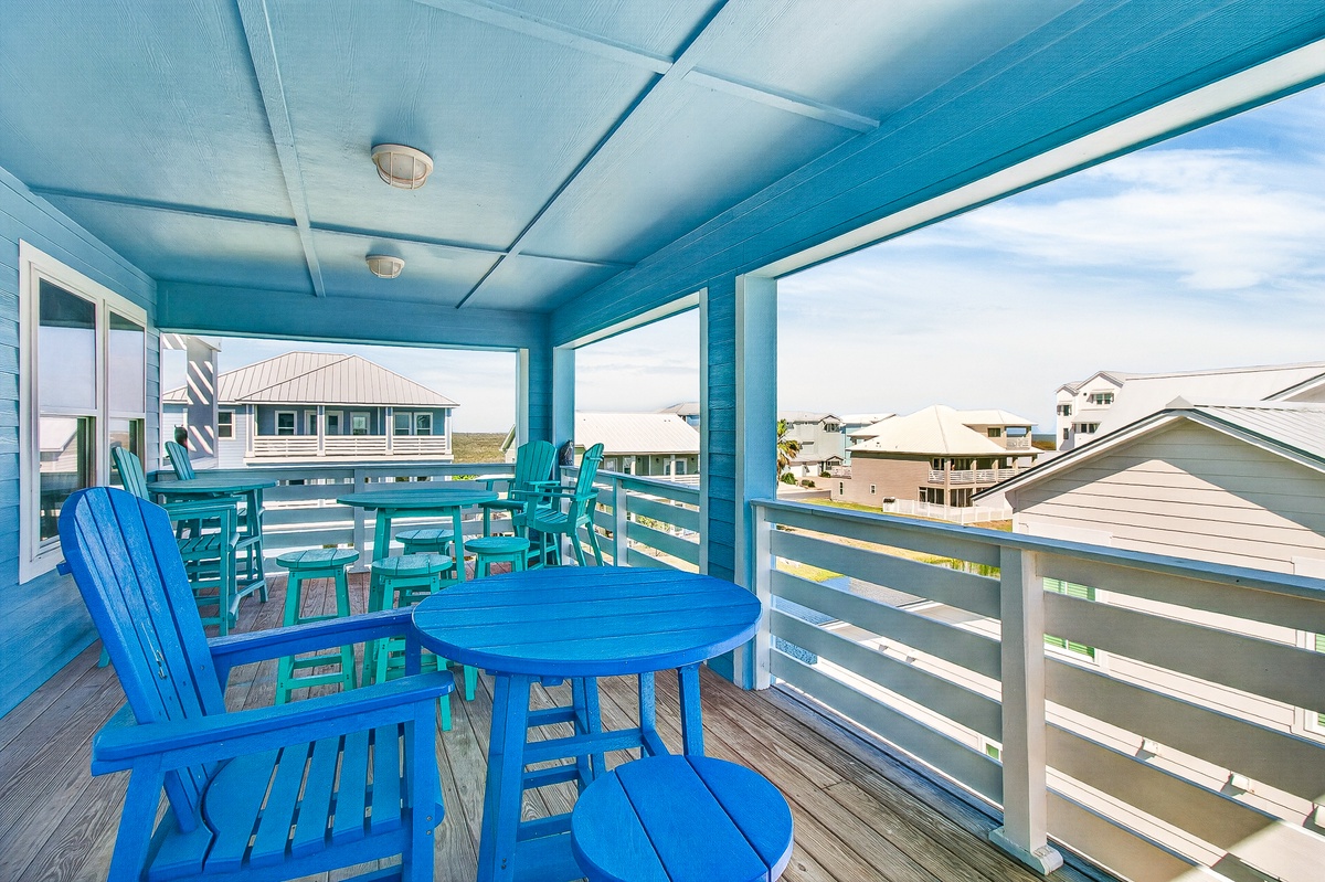 Your private covered balcony offers coastal charm with bright blue furniture and peaceful neighborhood views for morning coffee or sunset relaxation.