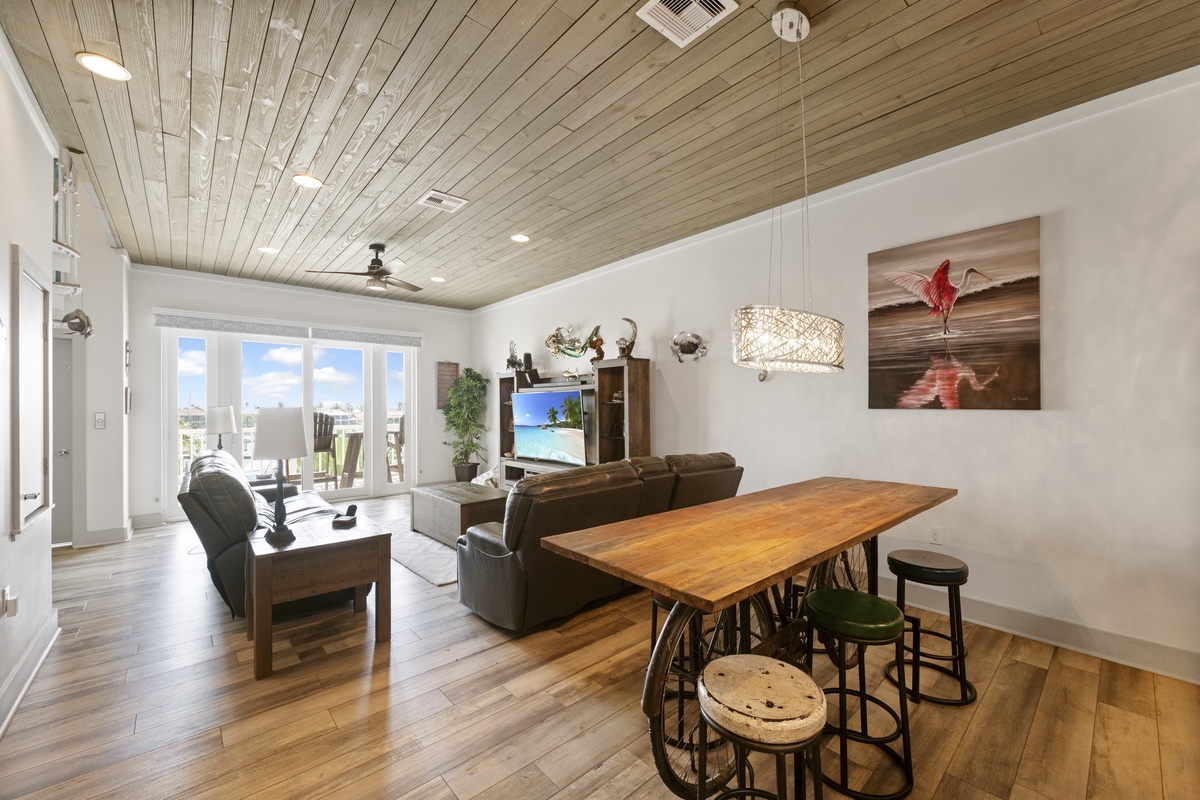 Relax in your open-plan living space with rustic wood ceiling, modern kitchen island, and French doors opening to your private patio.