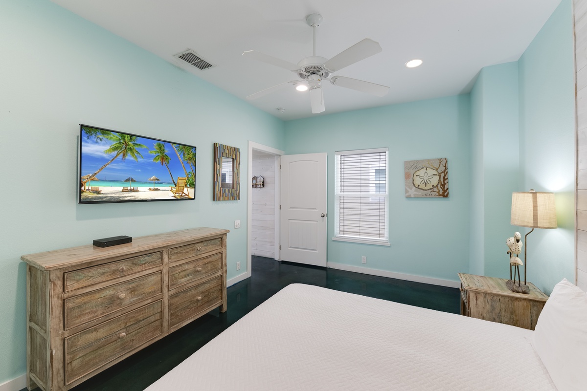 Your coastal-themed bedroom features a wall-mounted TV and calming turquoise walls that create a peaceful retreat for restful nights.