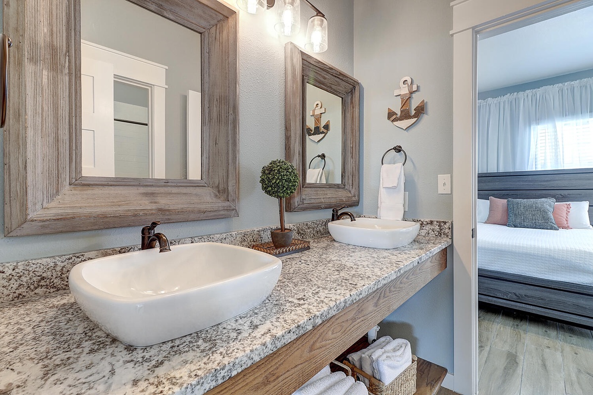 Your nautical-themed ensuite features dual vessel sinks on granite counters, creating the perfect morning routine space.