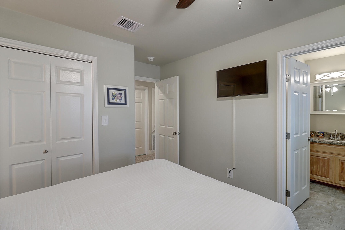 Relax in your peaceful bedroom featuring a plush bed, wall-mounted TV for cozy nights, and an ensuite bathroom just steps away.