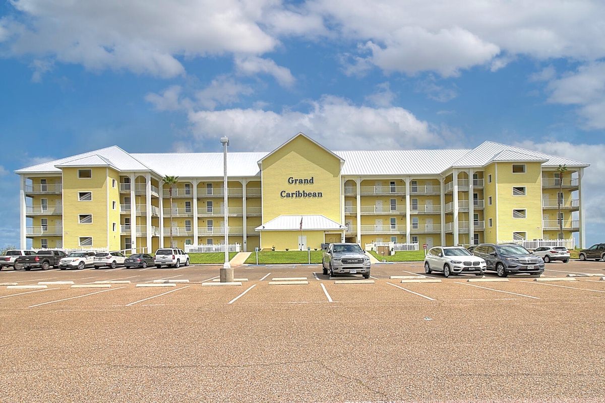 The Grand Caribbean resort building stands prominently with ample parking spaces and a welcoming entrance area.