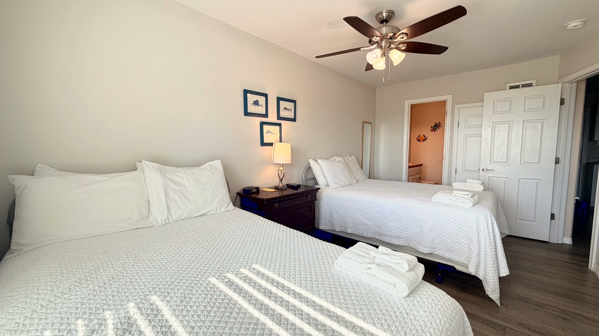 Settle in for a restful night in this cozy bedroom, featuring two comfortable beds with crisp white linens and coastal-inspired touches.