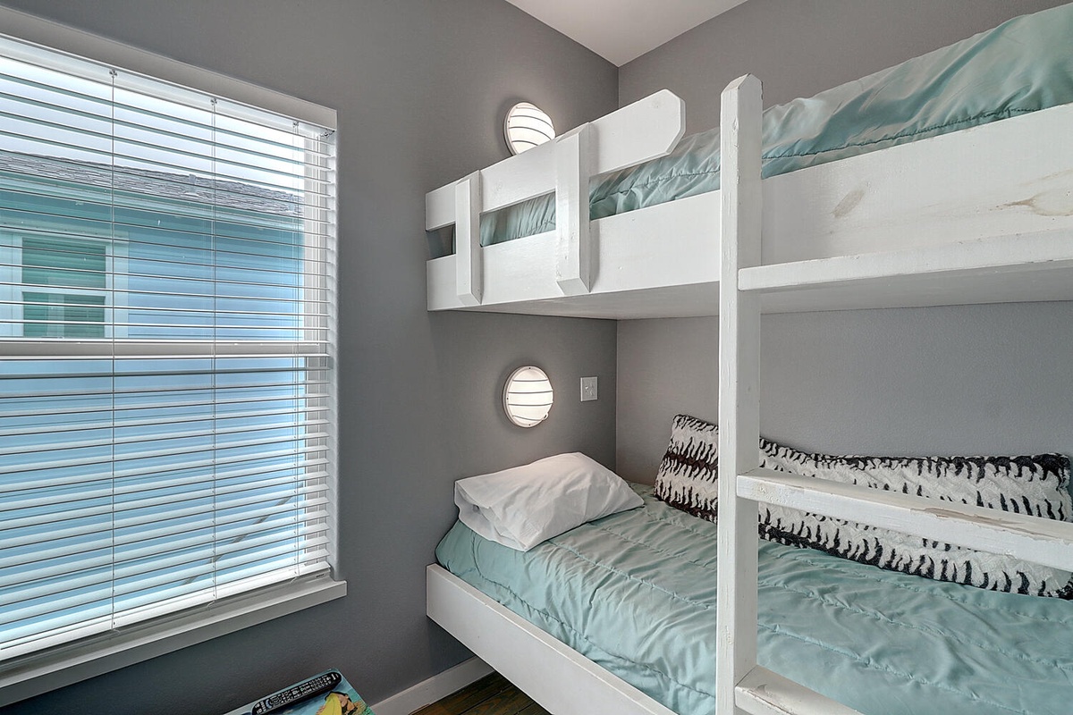 Cozy bunk beds await your little adventurers, featuring soft teal linens and built-in reading lights for bedtime stories.