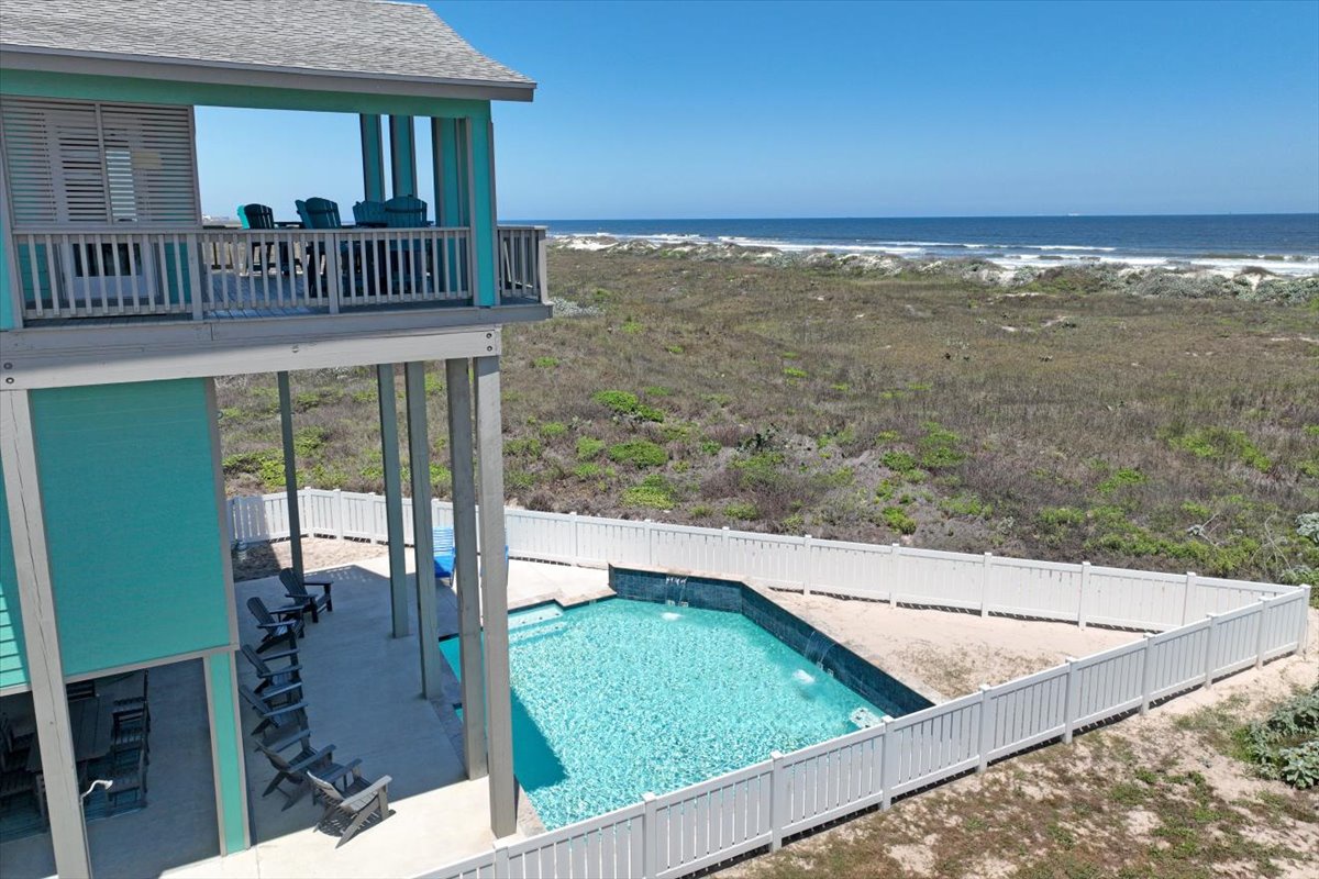 Beachfront property featuring elevated deck with ocean views, private pool, and direct beach access through coastal dunes.