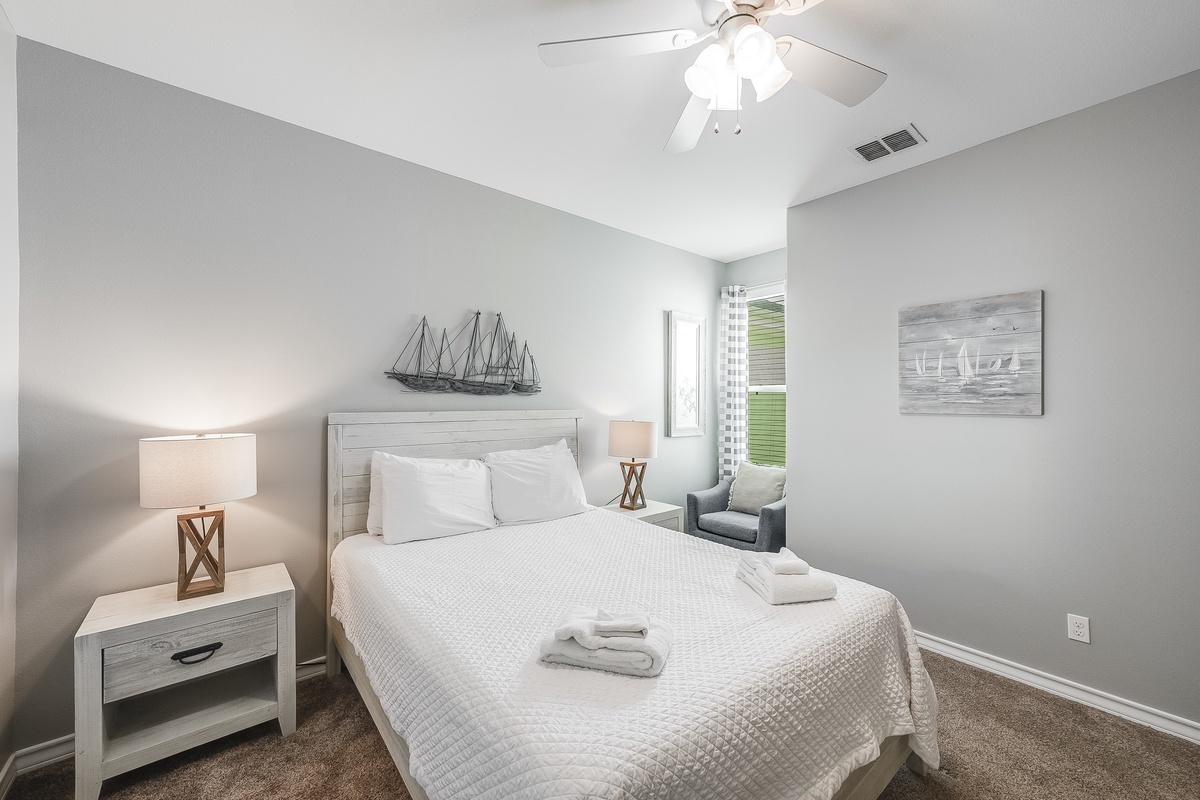 Unwind in your serene bedroom featuring coastal decor, crisp linens, and gentle ceiling fan breeze for restful nights.