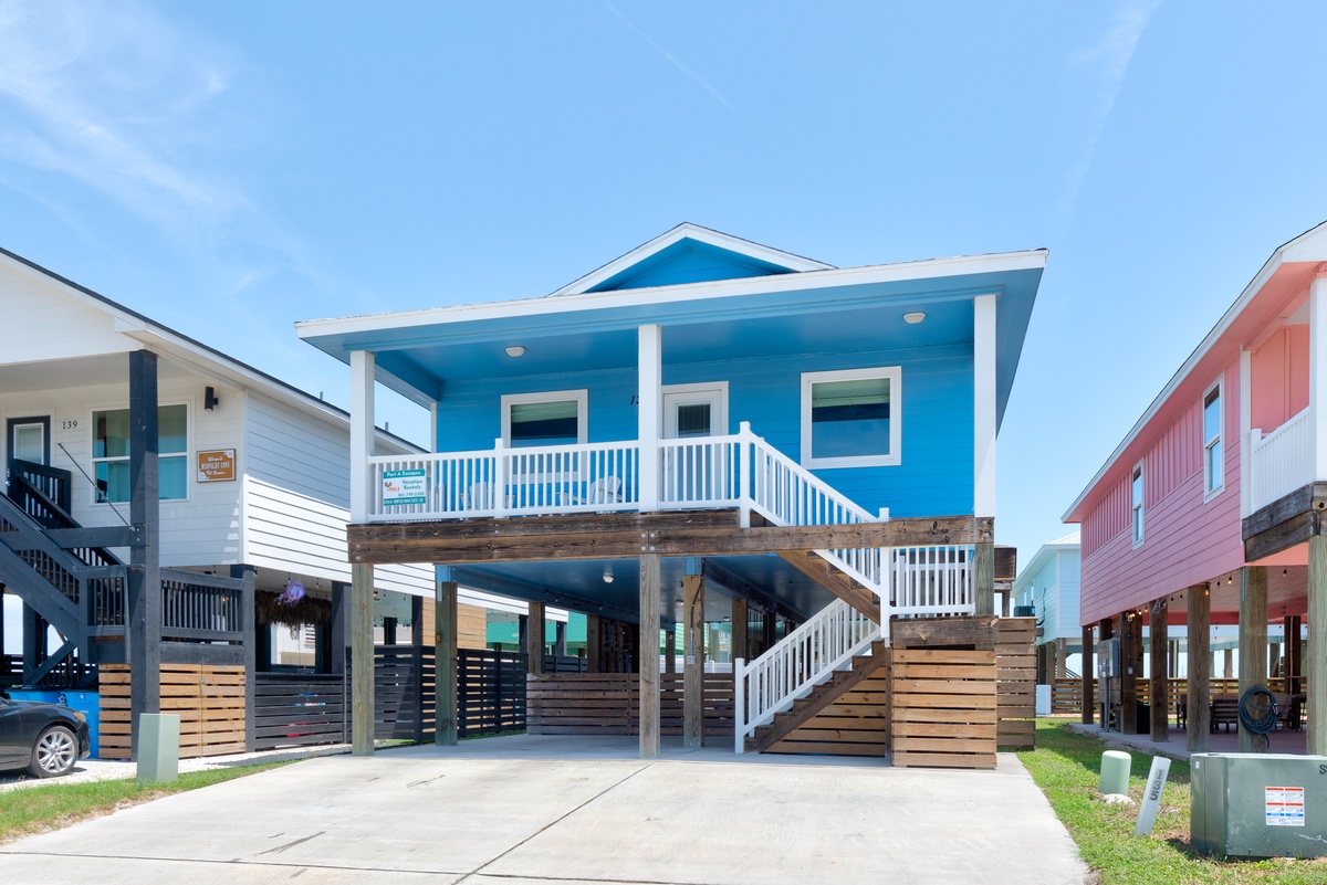 A vibrant coastal retreat elevated on sturdy pilings, with a welcoming covered porch and dedicated parking space steps from your door.