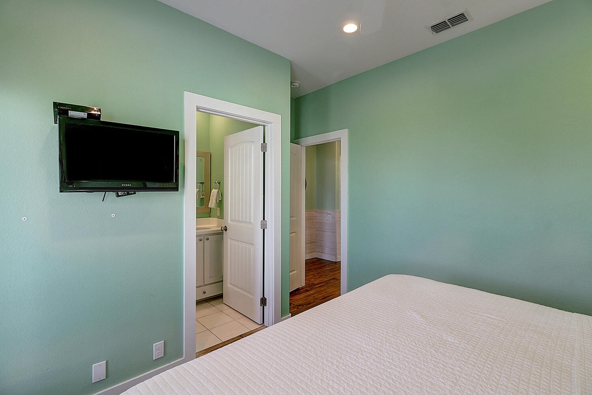 Relax in your tranquil bedroom with calming mint walls, wall-mounted TV for entertainment, and convenient ensuite bathroom access.