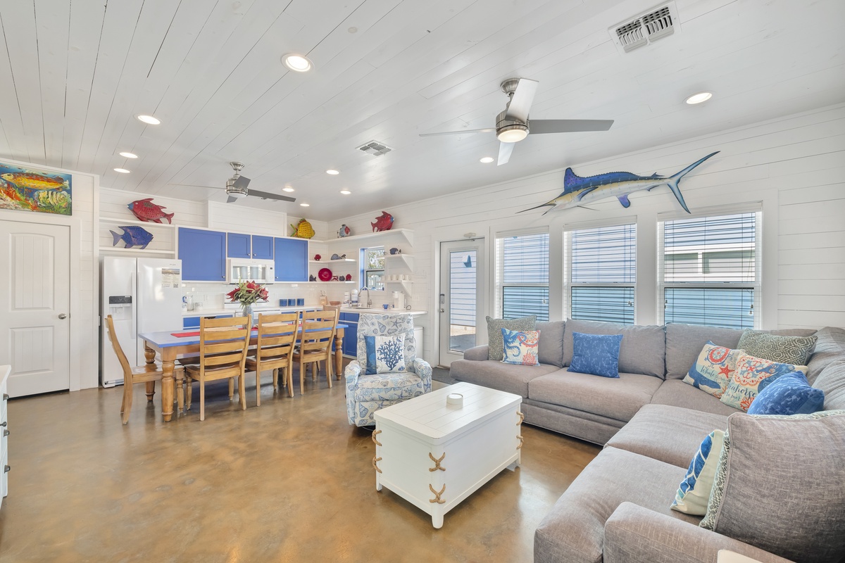 Relax in this coastal-themed living space where colorful fish art and nautical touches create your perfect beach getaway atmosphere.