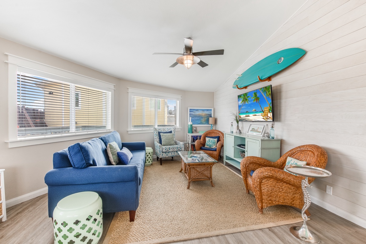 Your coastal-themed living room awaits with a blue sofa, wicker chairs, and beachy decor creating the perfect seaside retreat atmosphere.
