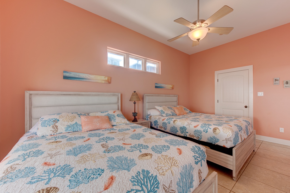 Your coastal-themed bedroom features two comfortable beds with ocean-inspired linens, letting you drift off to beach dreams beneath the gentle ceiling fan.