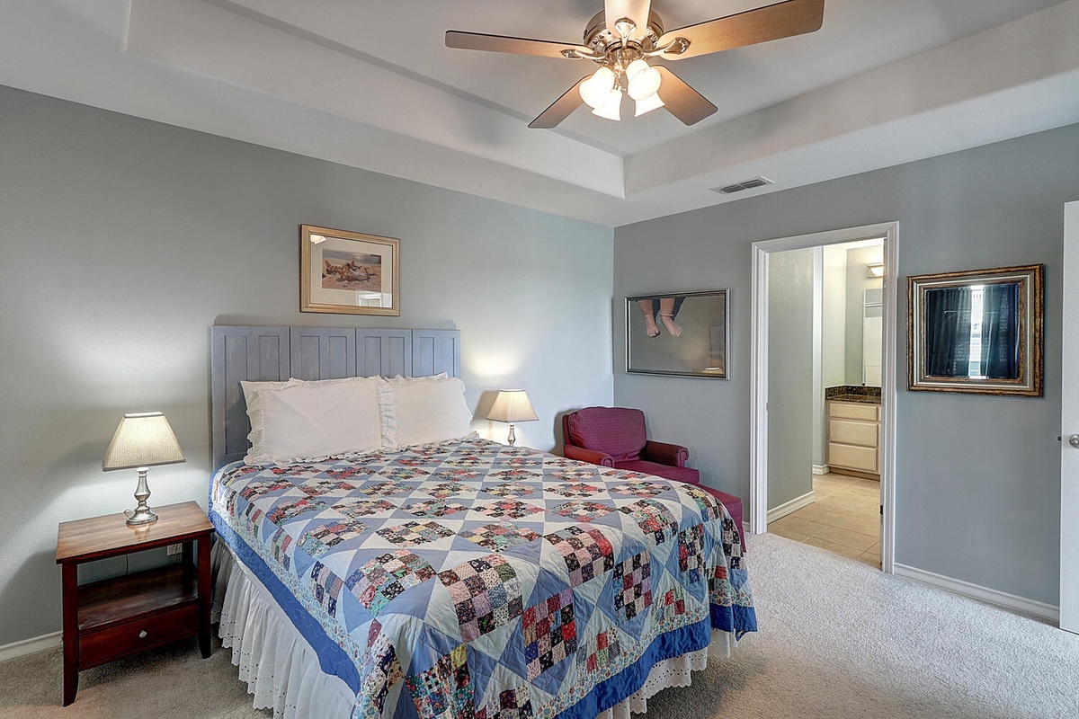 Drift into peaceful sleep under the gentle ceiling fan in this serene bedroom, complete with cozy reading chair and thoughtful touches.