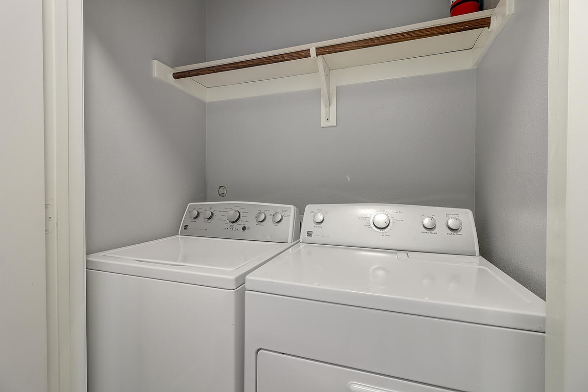 Keep your clothes fresh during your stay with this convenient in-unit laundry setup, complete with shelf space for easy organization.