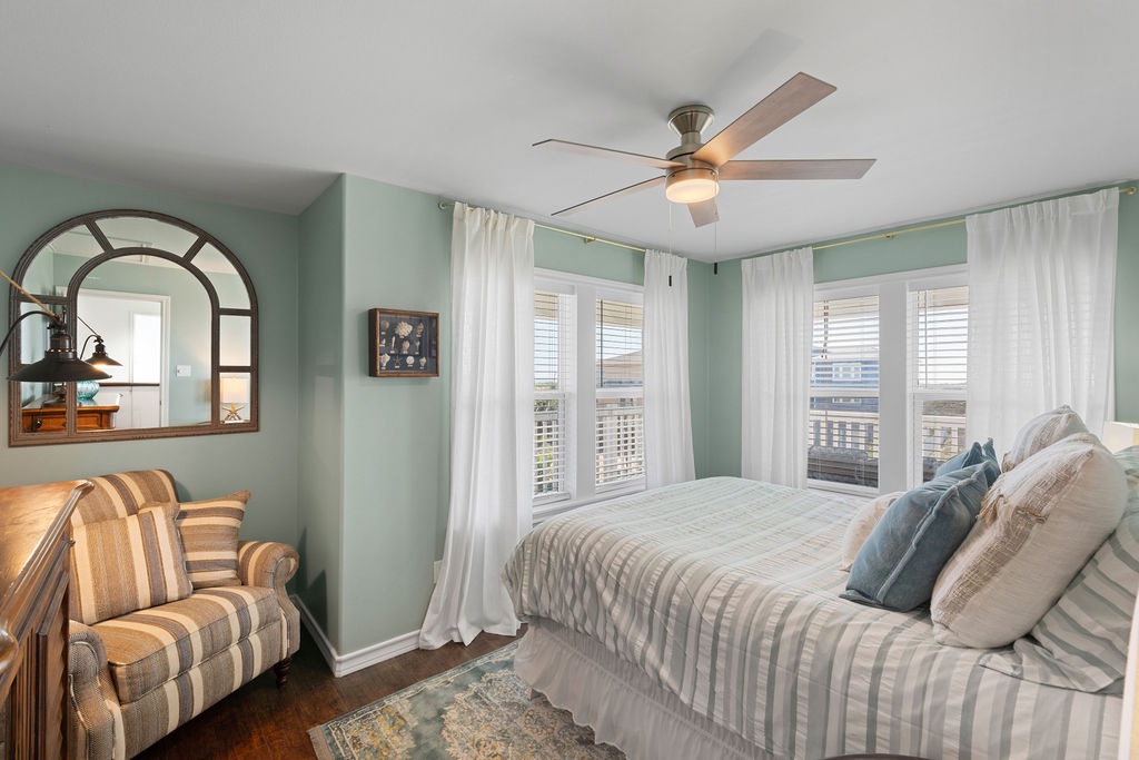 Drift off to peaceful sleep in this serene bedroom with soft seafoam walls, crisp linens, and a gentle ceiling fan.