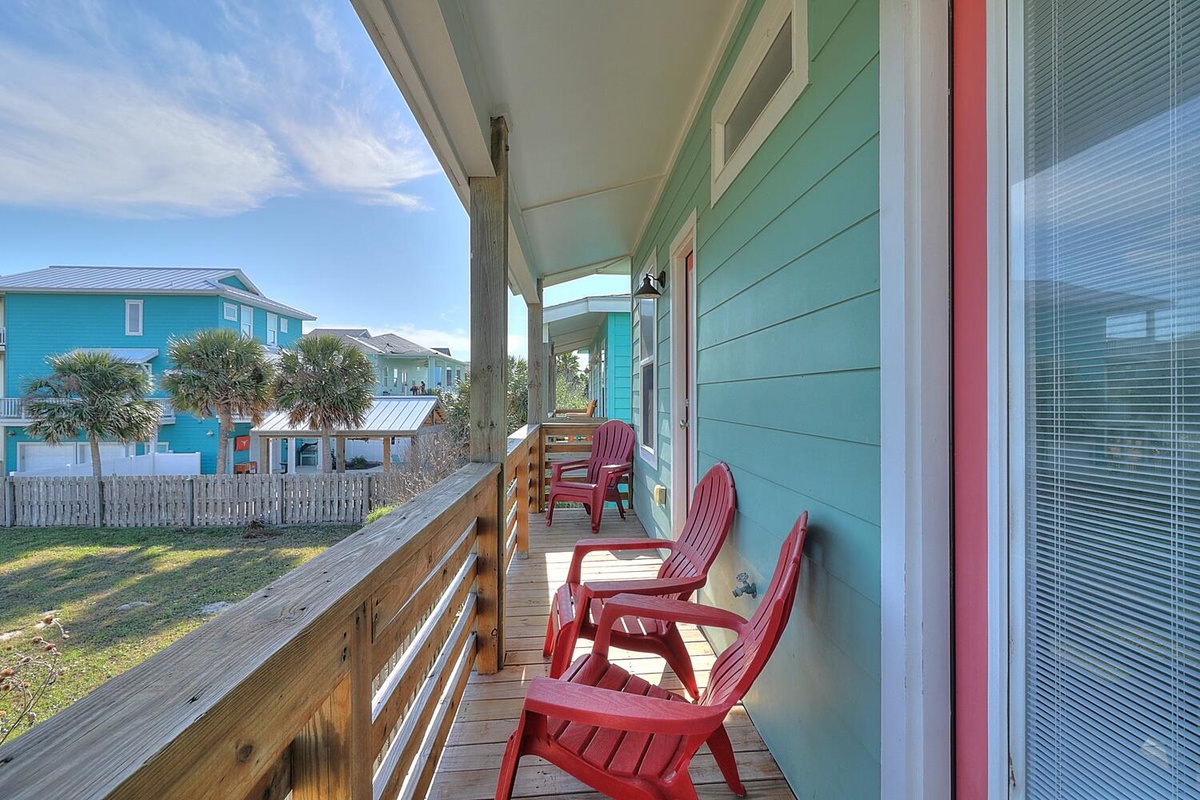 Unwind on your private covered deck with red Adirondack chairs, taking in views of the charming neighborhood and palm trees.