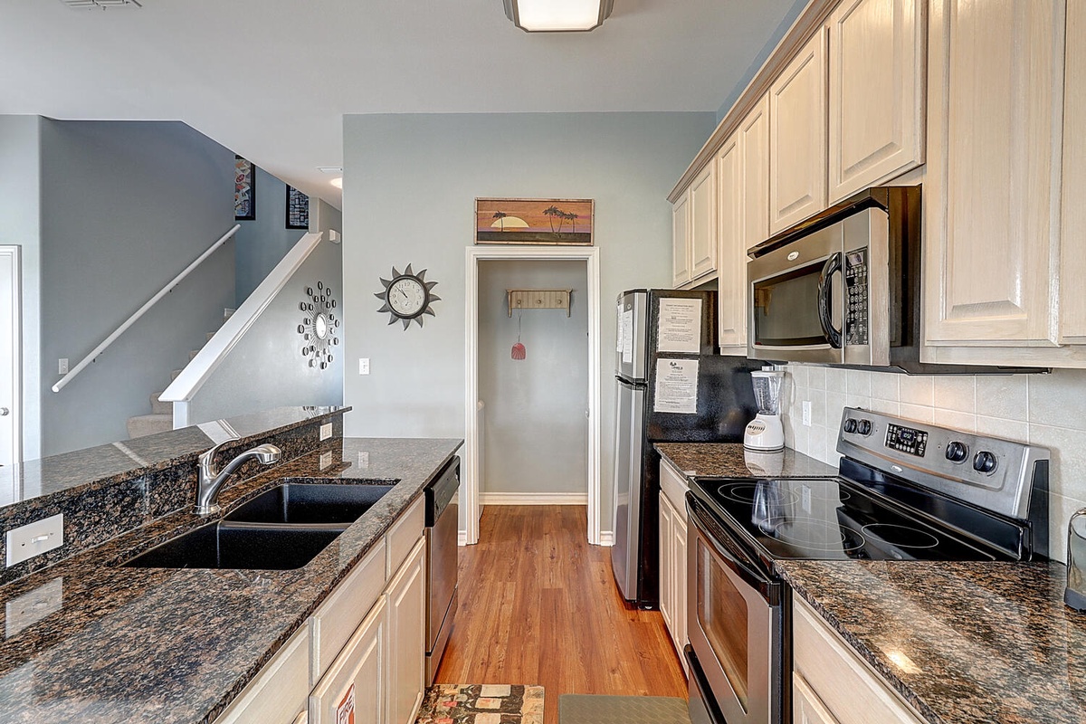 Your fully equipped kitchen awaits with granite counters, modern appliances, and warm wood floors - perfect for preparing meals during your stay.