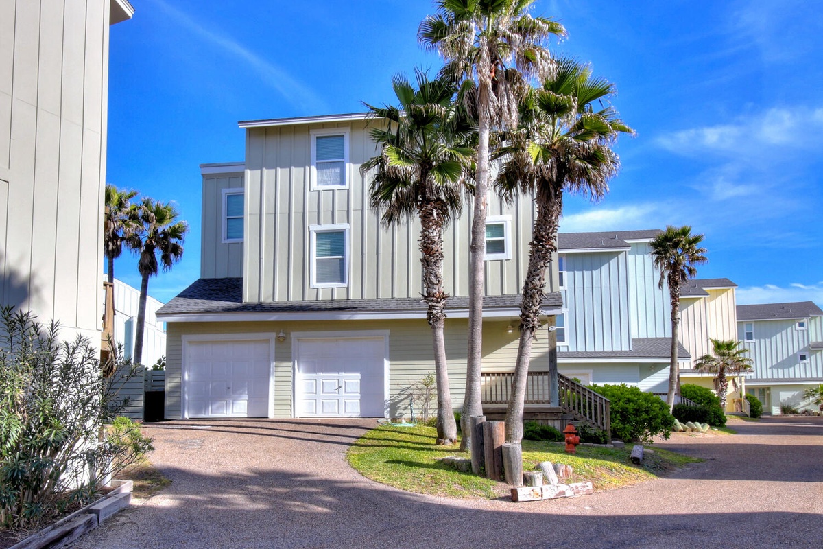 Modern beach house with palm trees and garage parking in a quiet coastal neighborhood.