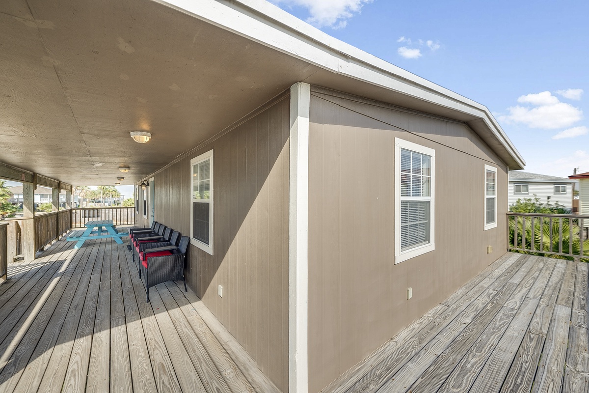 Spacious wraparound deck with comfortable seating where you can relax and enjoy the coastal breeze under covered outdoor living space.