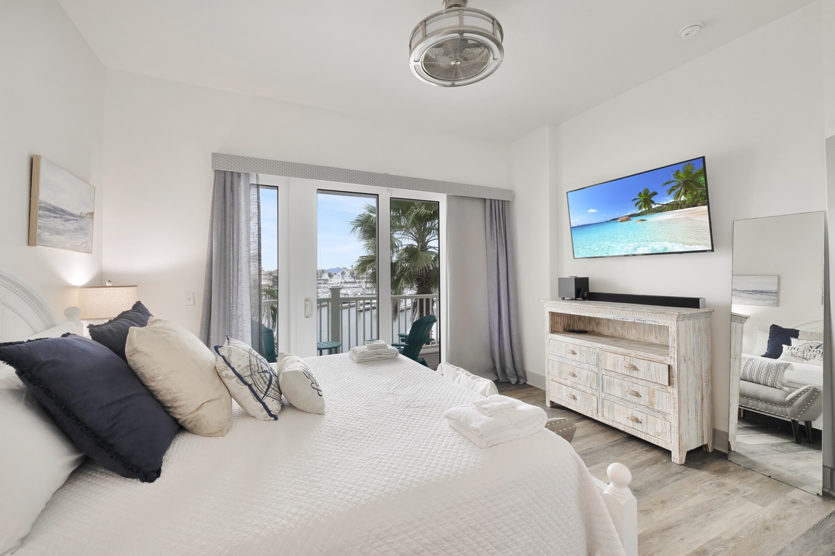 Your serene bedroom retreat features fresh linens and balcony access, with tropical beach scenes on TV to enhance your coastal escape.