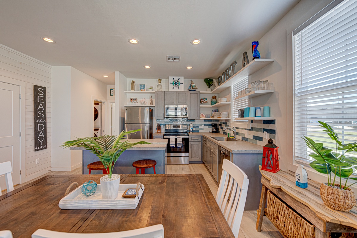 Cook together in your spacious open kitchen featuring stainless steel appliances, coastal-themed decor, and a breakfast island perfect for morning coffee.