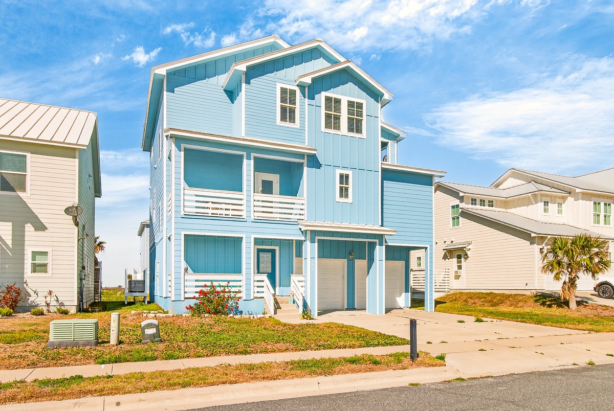 A charming three-story coastal home with bright blue siding and white trim, featuring multiple balconies and modern design in a seaside neighborhood.