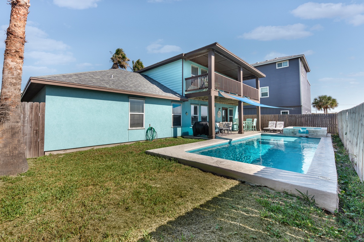 Charming coastal home with private pool and covered deck, surrounded by palm trees in a peaceful residential setting.
