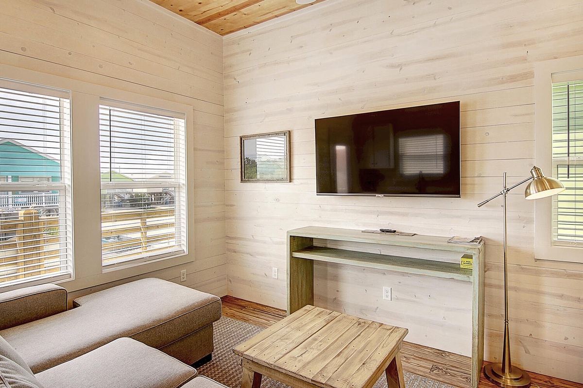 Unwind in your bright living space with warm wood walls, comfy seating, and modern entertainment setup for relaxing evenings.