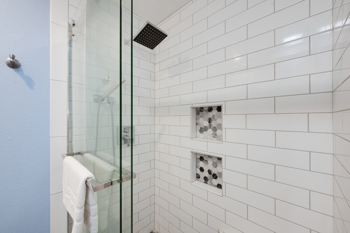Step into your stylish white subway-tiled shower with modern rainfall head and decorative built-in niches for your essentials.