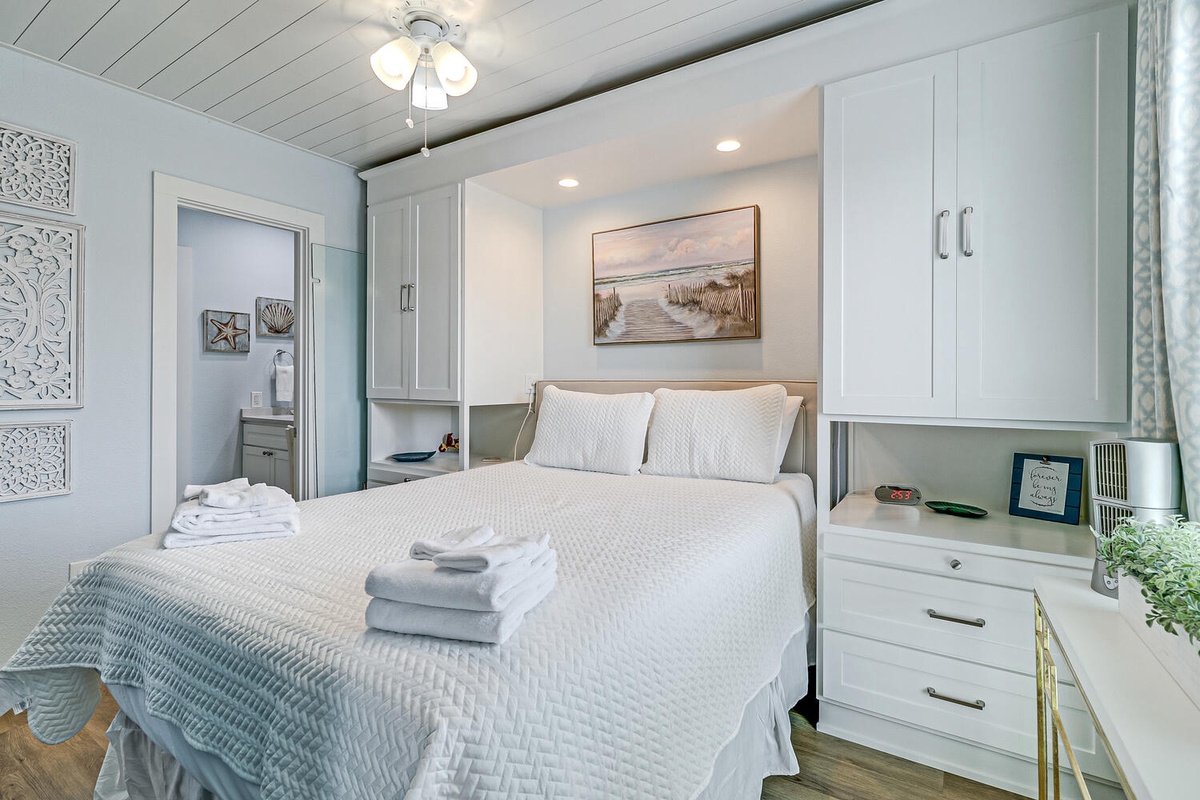 Sink into soft linens in your coastal-inspired bedroom, where clever built-in storage maximizes space and beachy artwork creates tranquil vibes for restful nights.