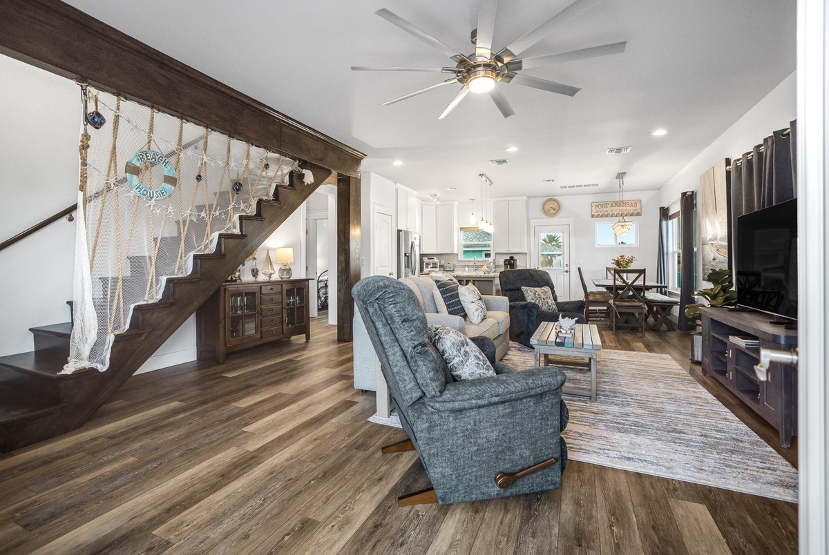 Relax in your spacious open-plan living area with coastal charm, featuring cozy seating and rustic wood details.