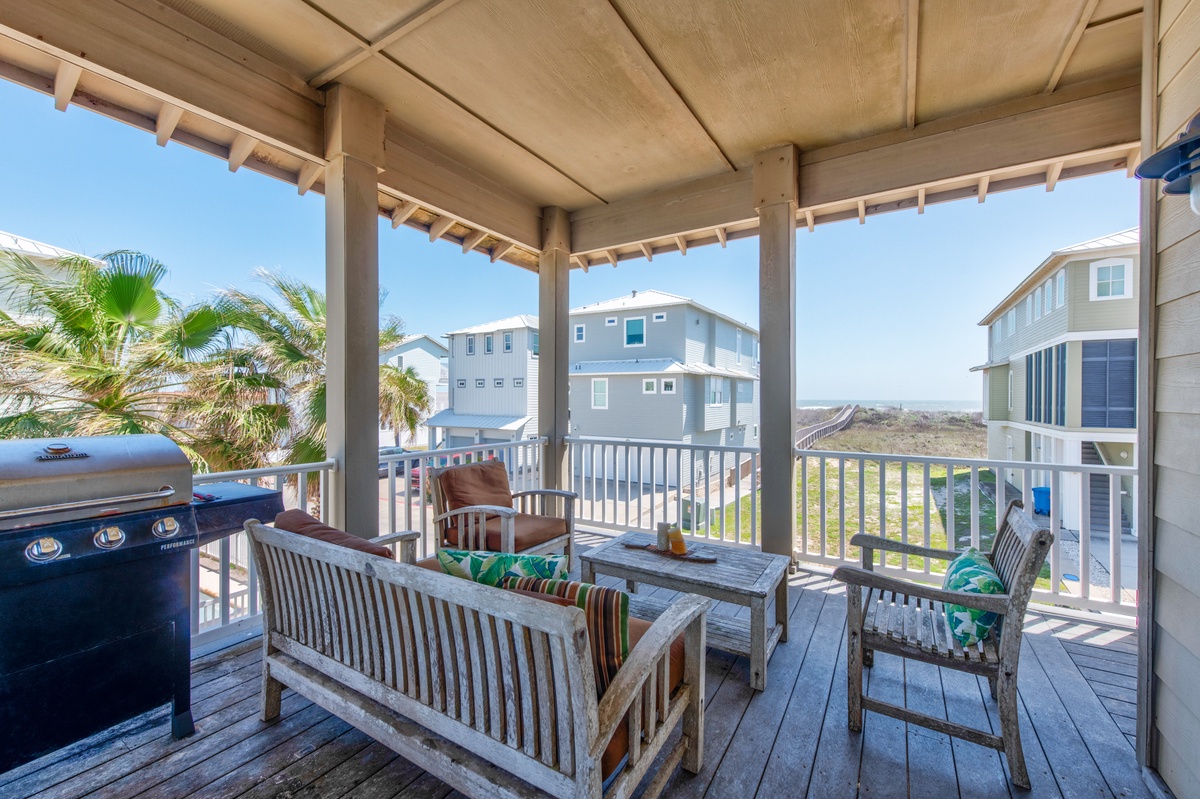 Your covered deck offers the perfect spot to grill and unwind with comfortable seating overlooking tropical palms.