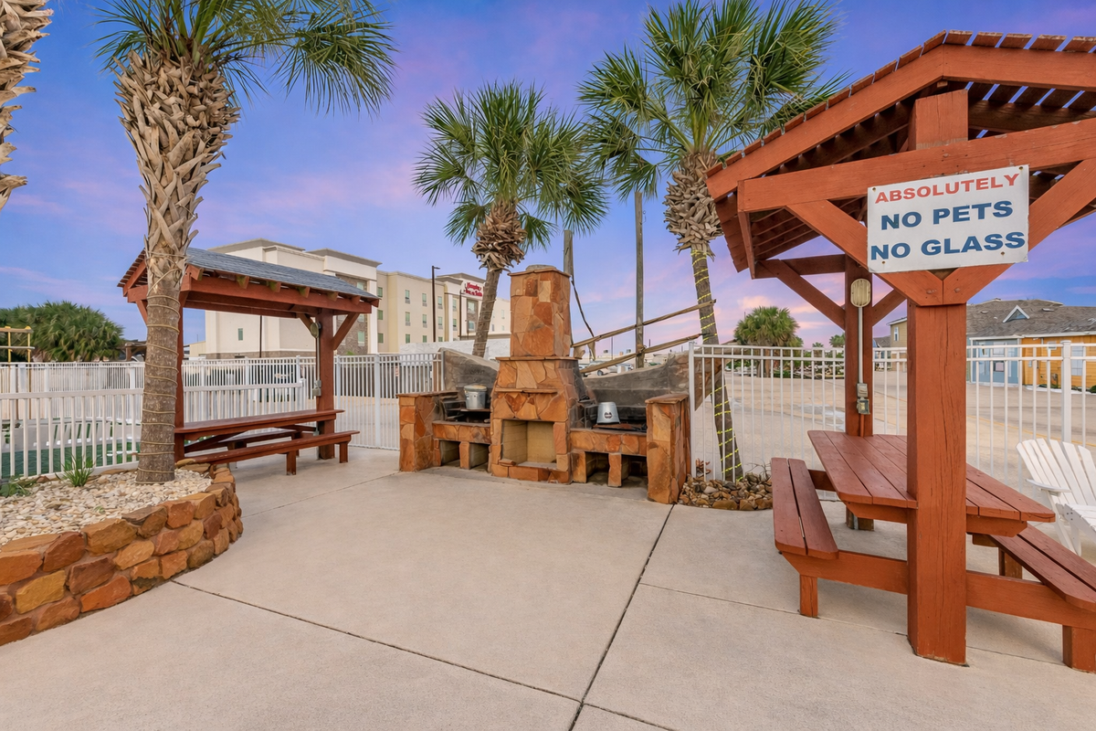 Fire up the grill and gather around your private outdoor kitchen, complete with stone fireplace and shaded seating under swaying palms.
