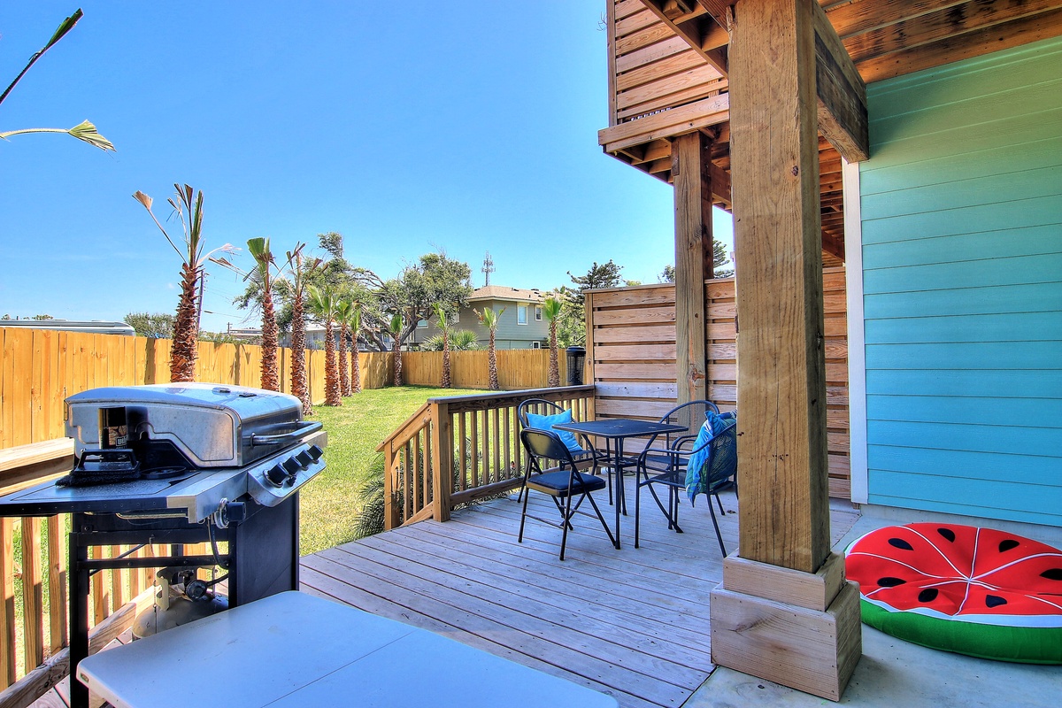 Your private deck awaits with BBQ grill and dining space, perfect for outdoor meals while enjoying the sunny backyard and tropical palms.