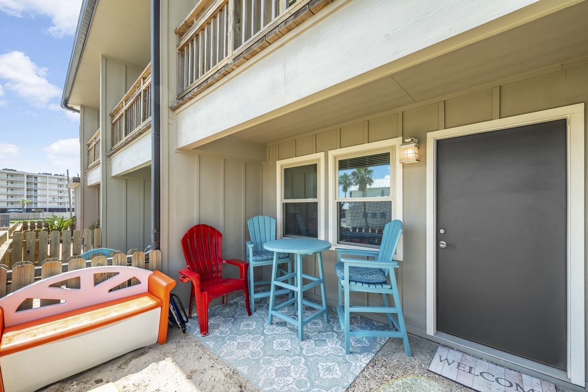 Step onto your private patio with colorful coastal chairs and bistro table, perfect for morning coffee or evening relaxation.