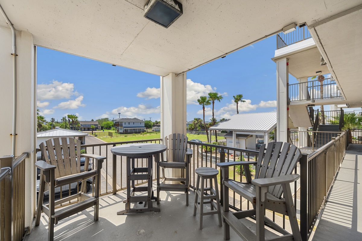 Relax on your private covered balcony with comfortable seating while enjoying views of the neighborhood and palm trees.