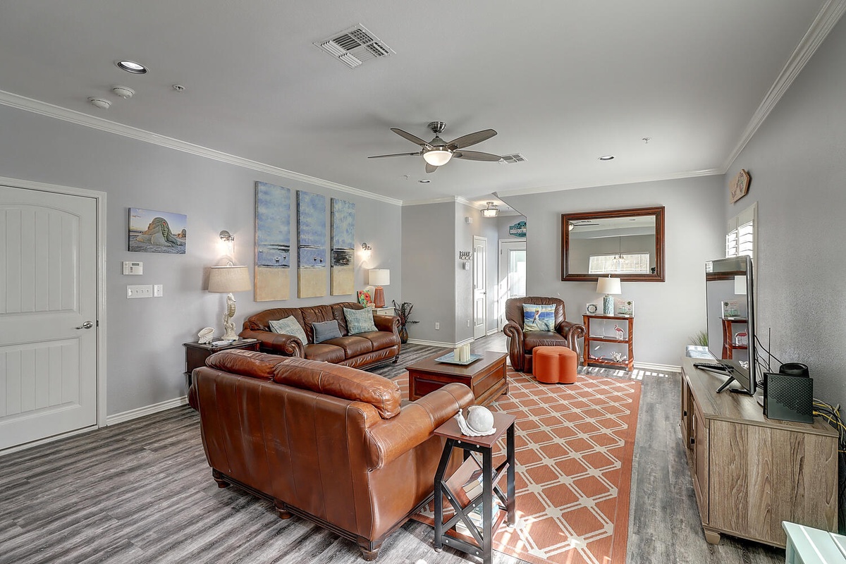 Sink into plush leather seating in your spacious living room, where coastal artwork and warm lighting create the perfect atmosphere for unwinding.