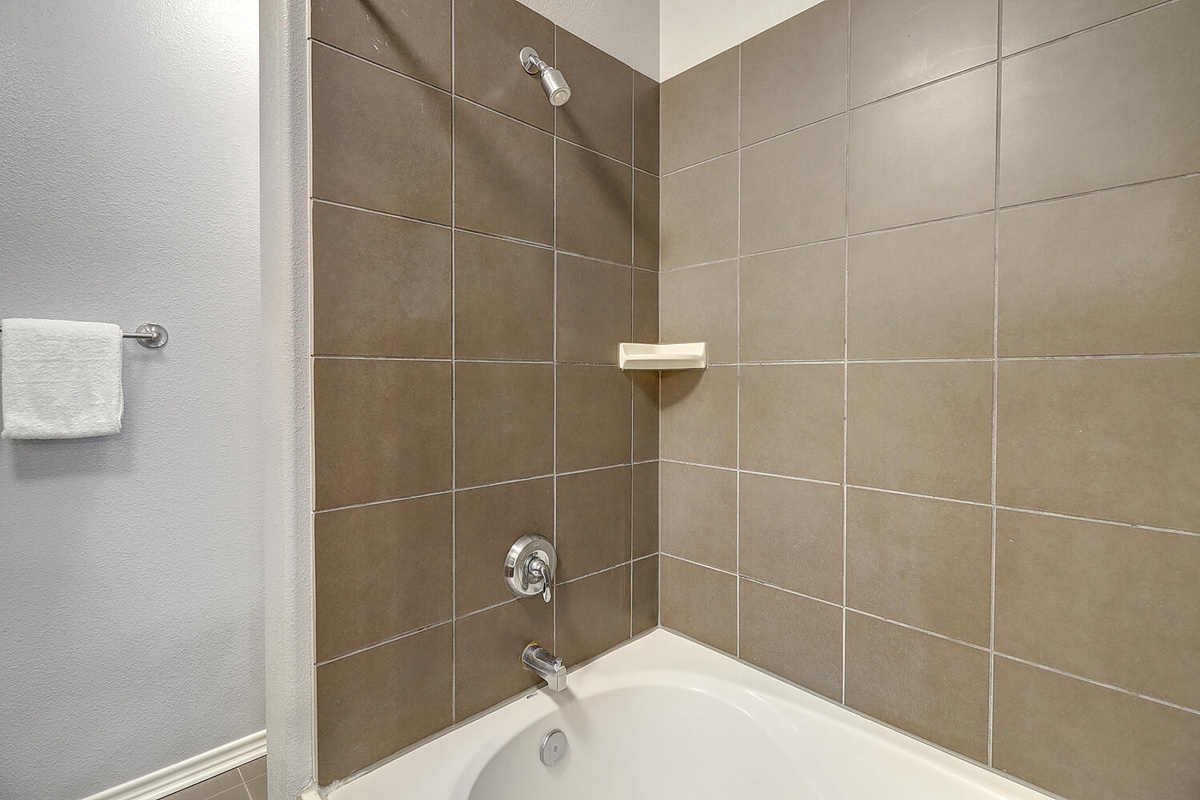 Unwind in your pristine tiled bath with modern fixtures and fluffy towels at arm's reach.