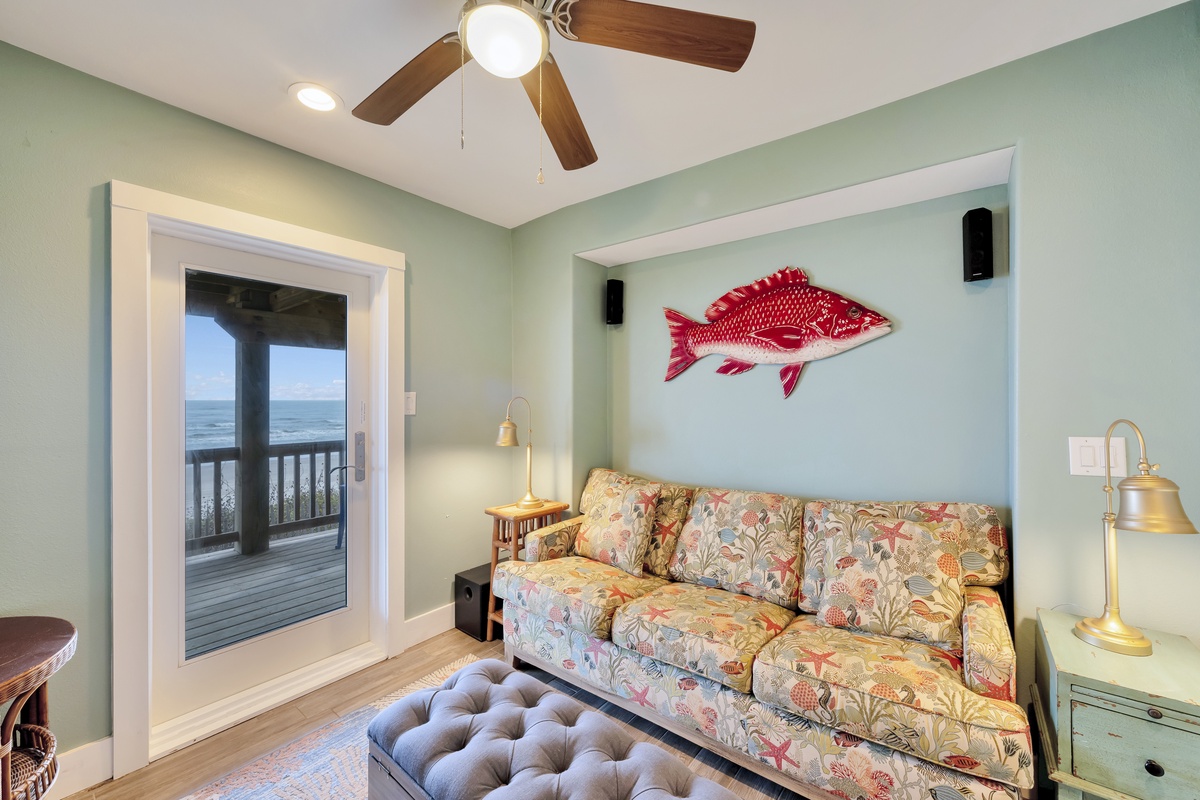 Relax in your coastal-inspired living room with sea views, where nautical charm meets comfort beneath a gentle ceiling fan.