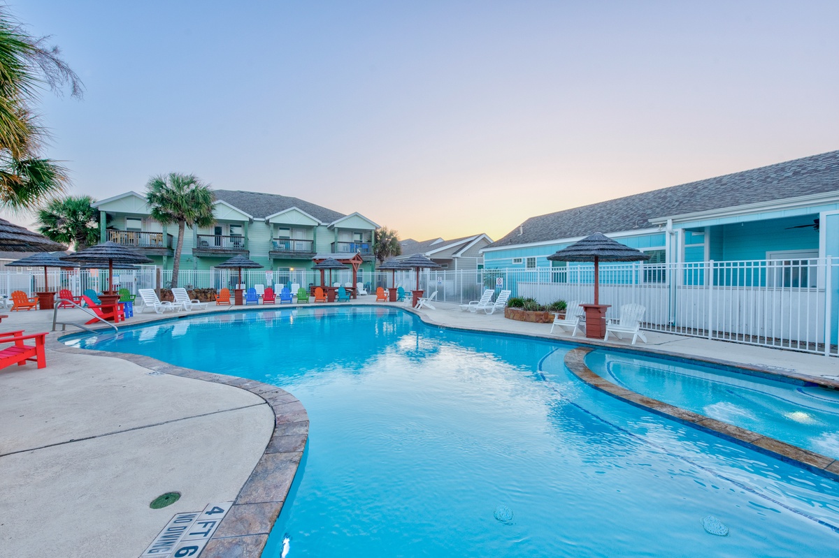 A sparkling community pool surrounded by colorful beach chairs awaits your relaxing afternoon swim under palm trees and coastal skies.