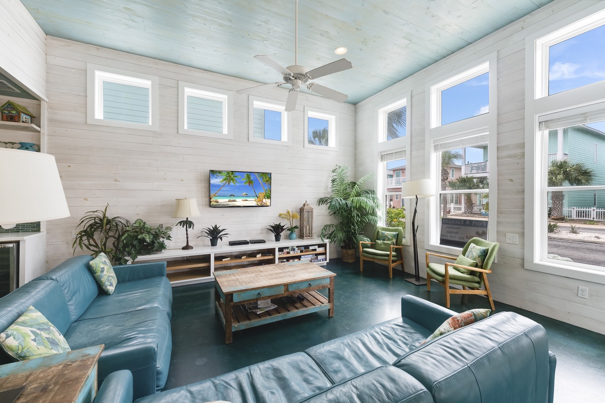 Sink into plush turquoise sofas while tropical breezes flow through floor-to-ceiling windows in your bright, airy living space with coastal charm.